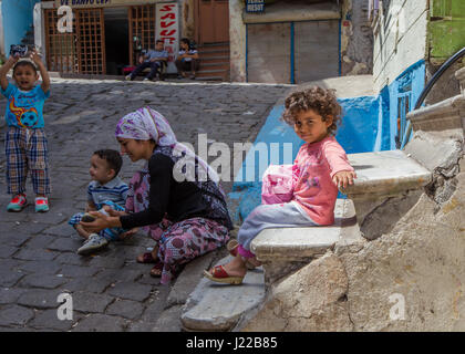 Woman in headscarf with three children all colourfully dressed, on the street in Balat area, Istanbul,  Turkey, in spring time. Stock Photo