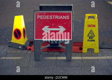 pedestrians this way sign on road path with wet floors warning Stock Photo