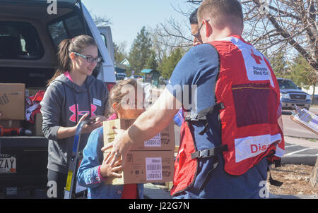 SCHREIVER AIR FORCE BASE, Colo. -- Katie Chandler hands her father, Capt. Allen Chandler, 6th Space Operations Squadron, a box of fire alarms that 310th Space Wing volunteers will install for local families during a Home Fire Campaign event on Saturday, Apr. 15th, 2017. The Red Cross responds to approximately 64,000 disasters each year with the vast majority being home fires, resulting in a goal to reduce fire-related deaths and injuries. (U.S. Air Force photo/Senior Airman Laura Turner) Stock Photo