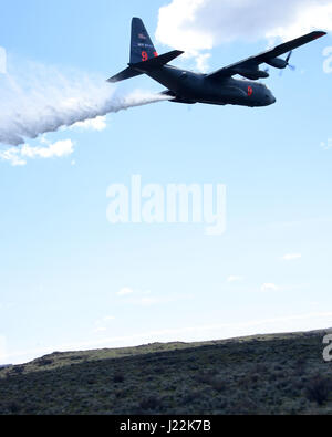 A C130h aircraft loaded with the MAFFS (Modular Airborne Fire Fighting System) from the 152rd Airlift Wing of Reno, Nevada drops a water line while training to contain wildfires just outside Bosie, Idaho. April 21, 2017. More than 400 personnel of four C-130 Guard and Reserve units — from California, Colorado, Nevada and Wyoming, making up the Air Expeditionary Group — are in Boise, Idaho for the week-long wildfire training and certification sponsored by the U.S. (U.S. Air National Guard photo by Staff Sgt. Nieko Carzis) Stock Photo