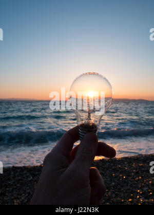 Man with light bulb against sun at beach concept Stock Photo