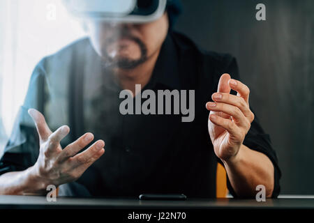 businessman wearing virtual reality goggles in modern office with mobile phone using with VR headset Stock Photo