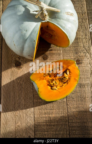 A Crown Prince Squash being cut and prepared for cooking on a wooden table. Stock Photo