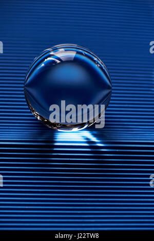 Glass globe or drop of water on a background of blue corrugated paper . Clean and Shine Stock Photo
