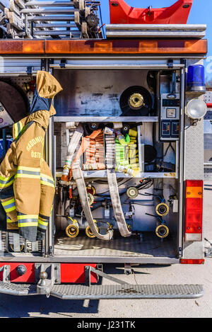 Brakne Hoby, Sweden - April 22, 2017: Documentary of public fire truck presentation. Truck seen from behind with visible hoses, uniform and tools. Stock Photo