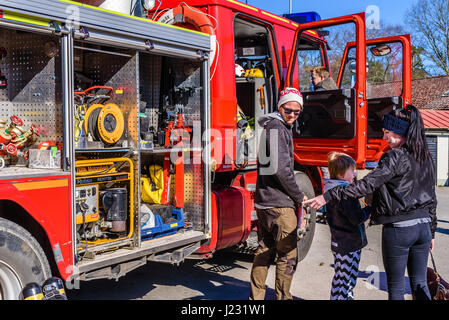 Brakne Hoby, Sweden - April 22, 2017: Documentary of public fire truck presentation. Woman accompanied by man and child, pointing at equipment inside  Stock Photo