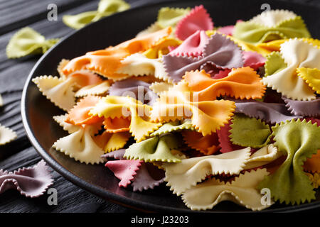 Beautiful Italian uncooked colored farfalle pasta close-up on a plate. horizontal Stock Photo