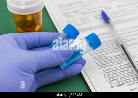Scientist with blue latex gloves holds vials of test in laboratory for analysis Stock Photo