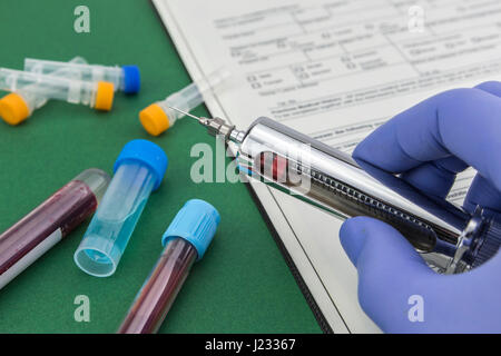 Scientist with blue latex gloves holds syringe special in laboratory for analysis Stock Photo
