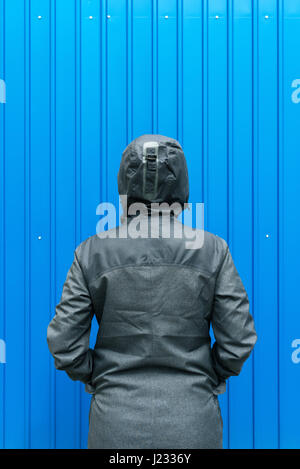 Facing problems and challenging obstacles in life, woman in hooded winter jacket in front of the wall Stock Photo