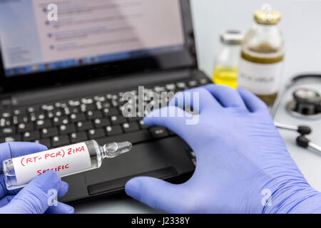 Scientist with blue latex gloves holds vials of ZIKA virus in laboratory for analysis Stock Photo