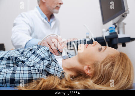 Optimistic woman getting thyroid ultrasound examination in the clinic Stock Photo