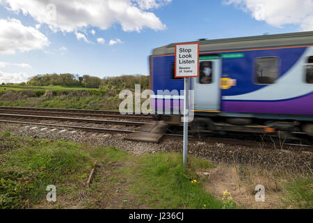 Train Passing a Pedestrian Crossing Warning Sign, Silverdale Lancashire, North West, England UK Stock Photo