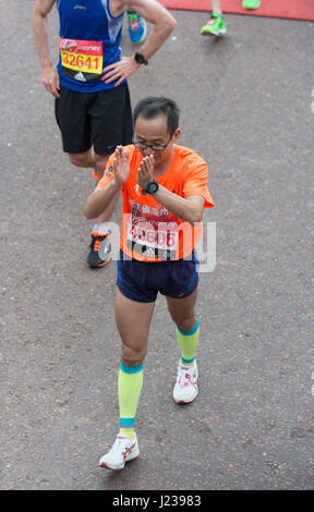 Mass event runners in the 2017 Virgin Money London Marathon cross the finishing line on The Mall. Credit: Malcolm Park/Alamy. Stock Photo