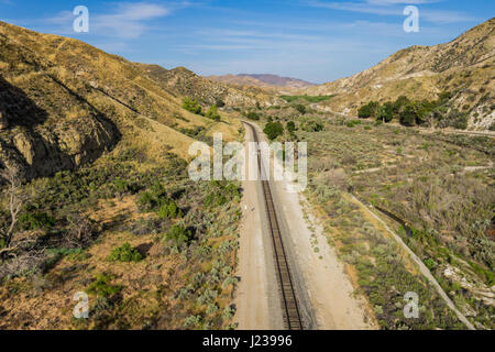 Straight long California desert railroad through a vally in the mountains. Stock Photo