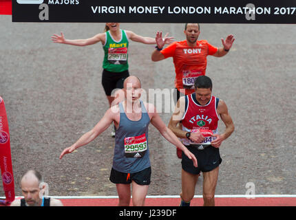 Mass event runners in the 2017 Virgin Money London Marathon cross the finishing line on The Mall. Credit: Malcolm Park/Alamy. Stock Photo