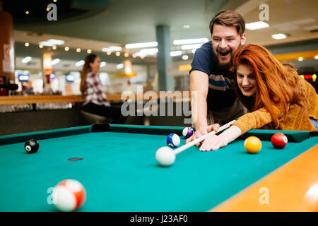 Beautiful happy couple playing billiards Stock Photo