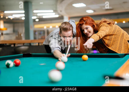 Beautiful happy couple playing billiards Stock Photo