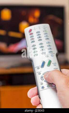 Person using a TV remote control Stock Photo