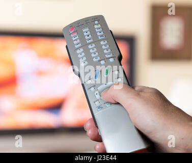 Hand holding and using a TV remote control to change channels, channel hopping Stock Photo