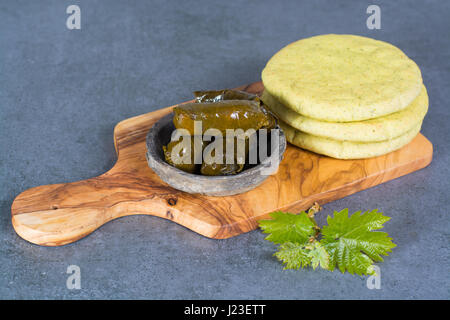 Mediterranean appetizer stuffed dolma from vine leaves and minced meat in bowl with garlic pita bread on wooden plank made fron olive tree Stock Photo