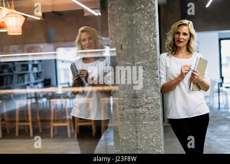 Beautiful businesswoman holding a folder in an office with a nice reflection Stock Photo