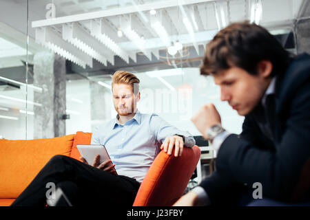 Business people looking at their devices and working Stock Photo