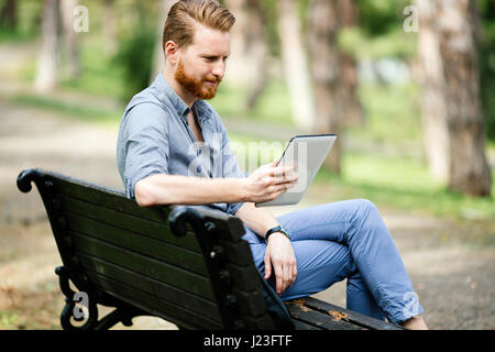 Businessman using tablet pc in park and relaxing