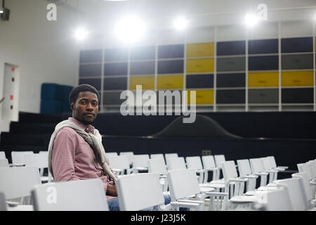 Serious student sitting on one of chairs in conference room Stock Photo