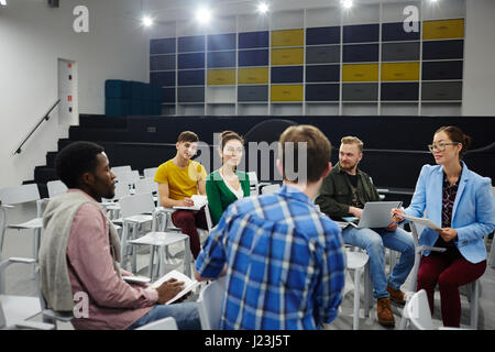 Group of students having talk in lecture hall Stock Photo