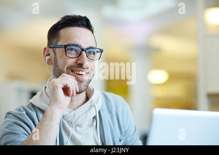 Portrait of contemporary adult man smiling while using laptop to video call somebody Stock Photo