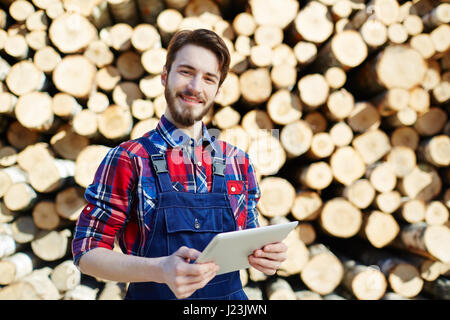 Happy young lumber with touchpad working on lumberyard Stock Photo