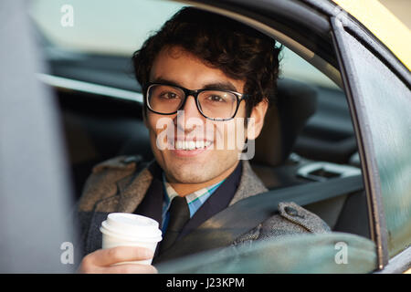 Happy man with hot drink looking through cab window Stock Photo