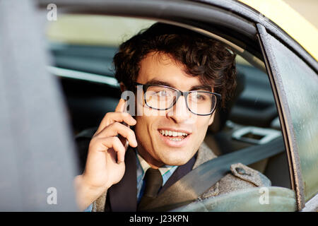 Mobile businessman speaking on cellphone while going to work by car Stock Photo