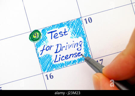 Woman hand with pen writing reminder Test for Driving License in calendar. Stock Photo