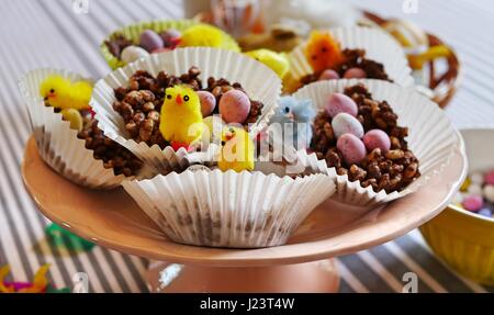 Homemade chocolate nests for Easter with chick decorations and colourful mini eggs Stock Photo