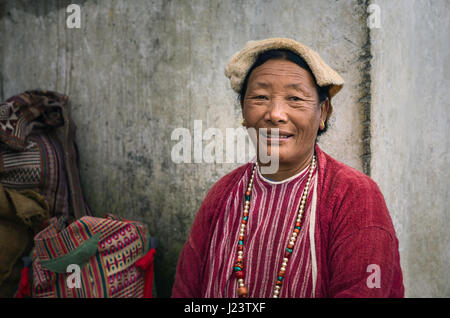 Candid portrait of a woman from the Monpa tribe dressed in traditional clothes and wearing beaded necklace in Tawang, Arunachal Prsdesh, India. Stock Photo