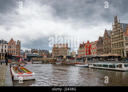View of Graslei (Grass Quay) and Korenlei (Corn Quay) with medieval buildings, tourist boats and unidentified tourists on a cloudy day. Ghent, Belgium Stock Photo
