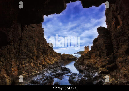 Rocky cave towards open sea at sunset near Bombo beach and Cathedral rocks of Pacific coast in Australia. Stock Photo