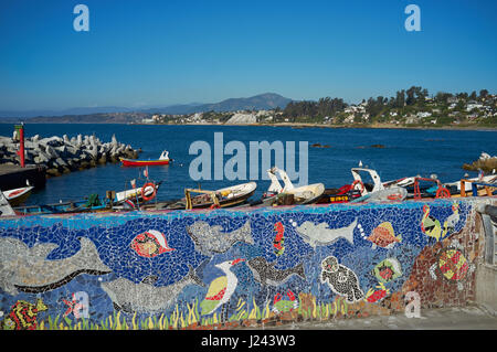 Colourful fishing boats behind the seawall on the Pacific Coast of Chile at Concon. Stock Photo