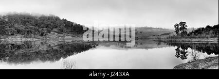Wide stlil panorama of Lake Lyell on Coxs river in Blue Mountains national park of Australia. Reflection of surrounding hills and farmlands in black-w Stock Photo