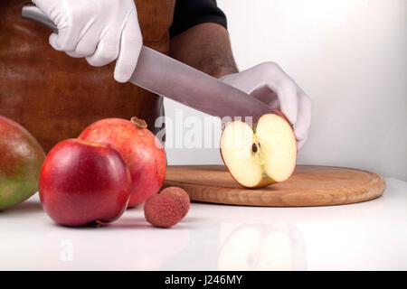 Man cutting an apple into half on a wooden cutting board Stock Photo