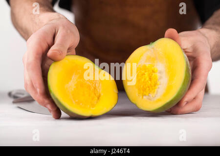 Mango fruit cut into two on white background. MAn's hands holding mango Stock Photo