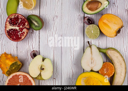 Fresh exotic fruits placed on a white wooden surface. Fruits cut into halves Stock Photo
