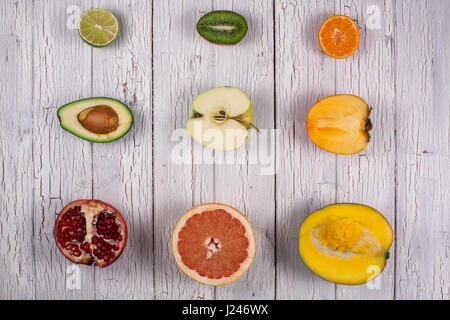 Ripe fresh fruits cut into halves and making rows on a wooden table Stock Photo