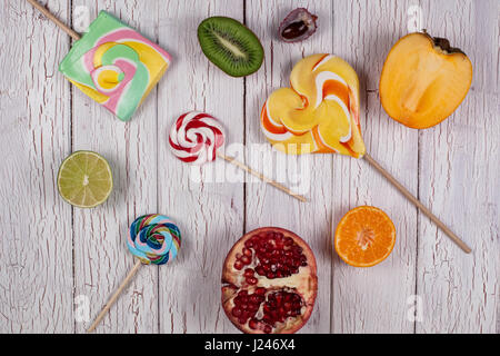 Composition of ripe fruit halves and colourful candies placed on a white wooden board Stock Photo