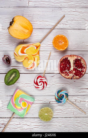 Halves of fruits and sweet candies placed on a wooden board Stock Photo