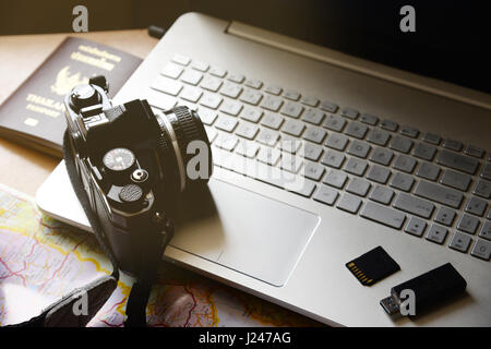 Vacation concept passport camera flash drive storage map notebook computer on wooden desk background Stock Photo