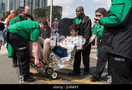 LONDON - April 23: Virgin Money London Marathon. St. John Ambulance First aiders help an injured runner in through Canary Wharf. Photo: © 2017 David Levenson/ Alamy Stock Photo