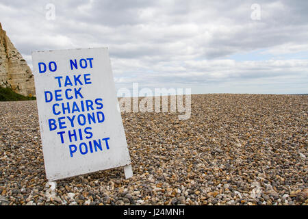 An informal sign or board on a the deserted pebble beach at Beer in , Devon, UK telling tourists that deckchairs are not permitted beyond this point. Stock Photo